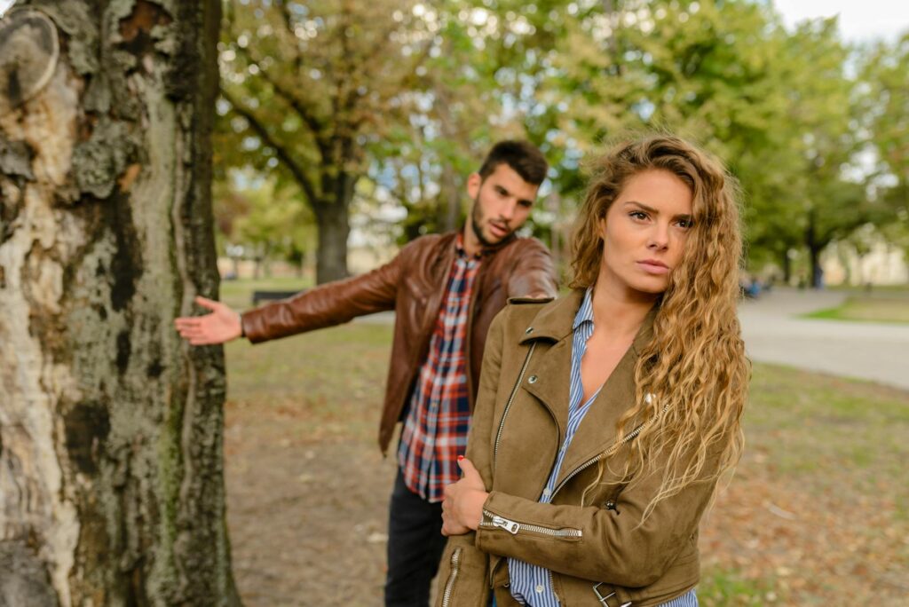 woman and man wearing brown jackets standing near tree