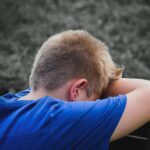 close up photo of sad child leaning on a wooden chair