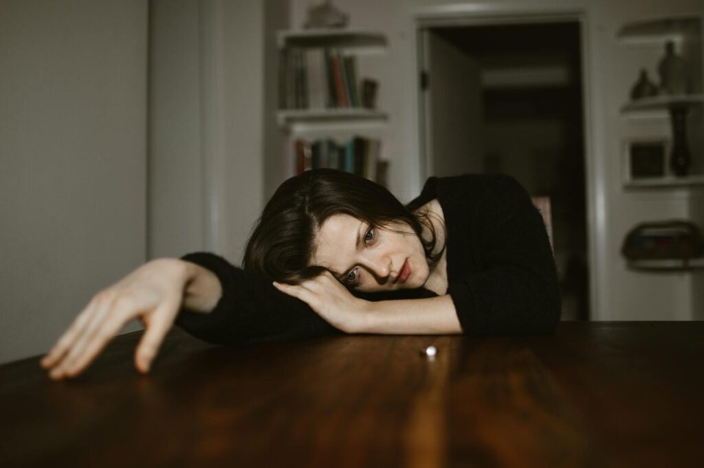 a sad woman resting her head on a wooden table