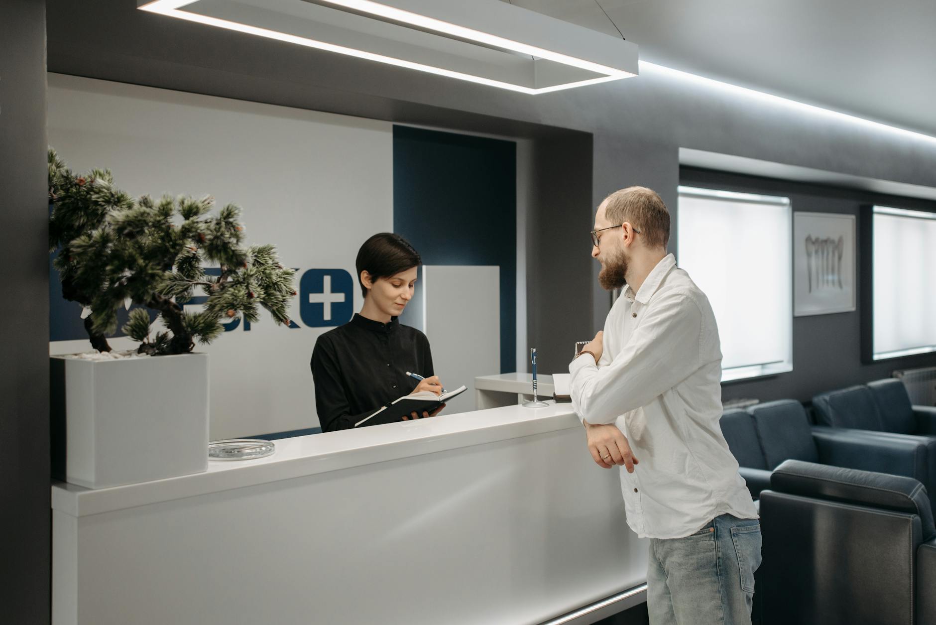 man talking to assistant at reception of dentist clinic