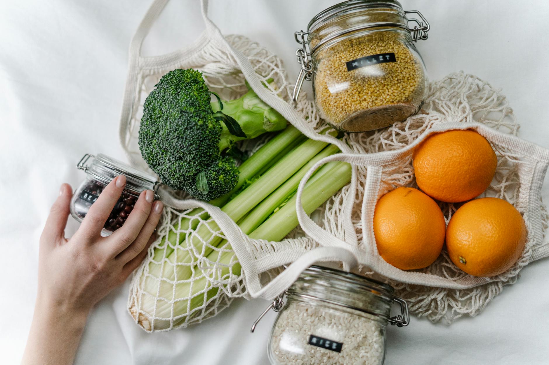green vegatables on table and person holding mason jar with spice