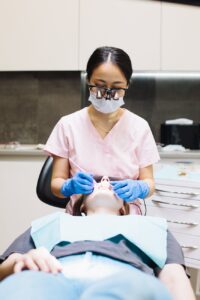 dentist in pink scrub examining a woman s teeth